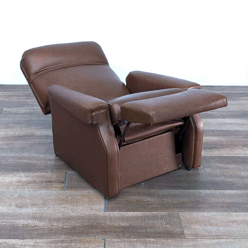 Reperch leather recliner with extended footrest and nailhead trim on wooden floor.
