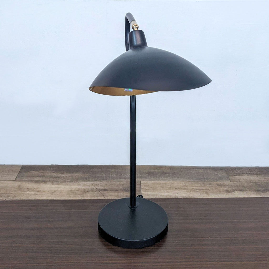 Black and gold Safavieh adjustable height table lamp with a mid-century design on a wooden surface.