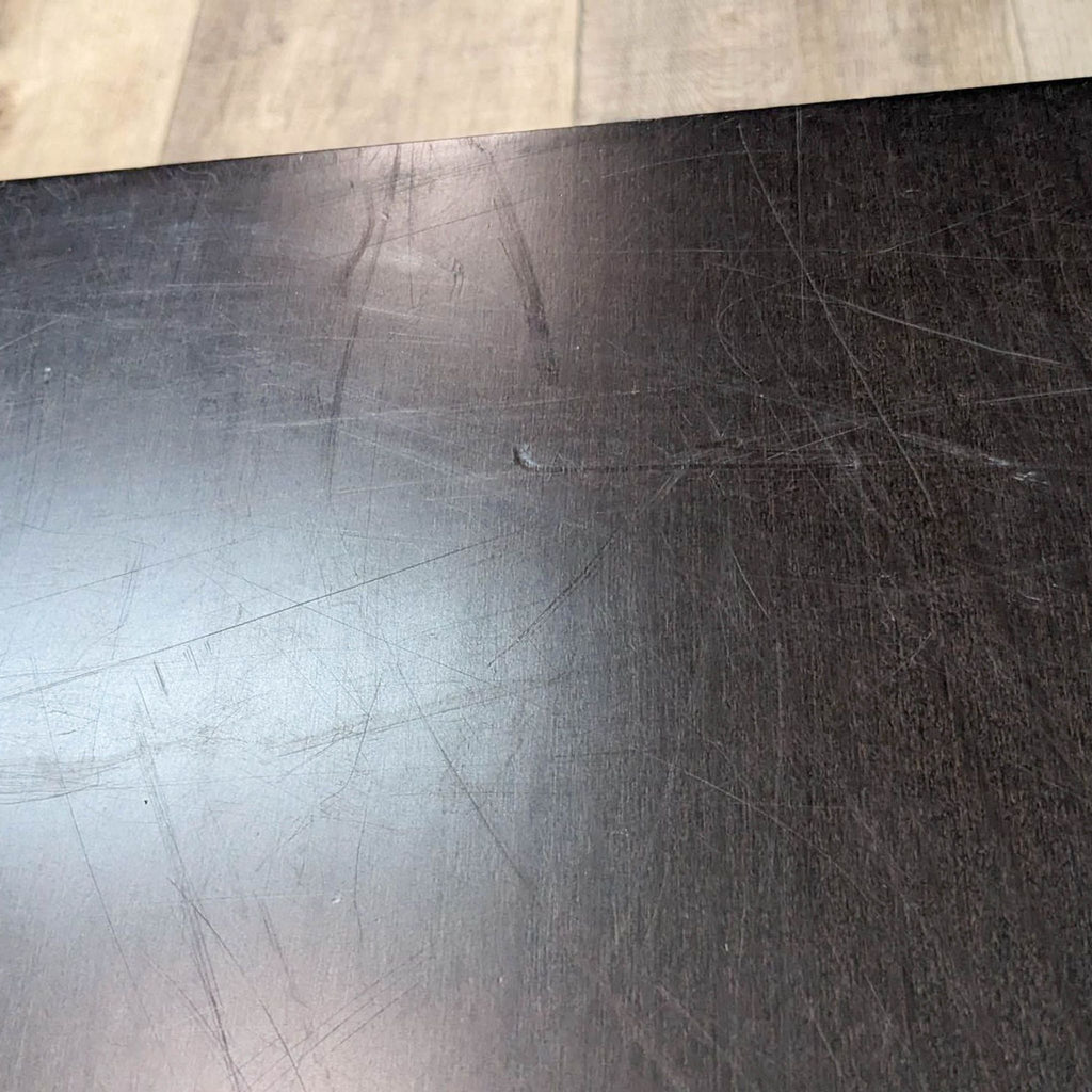 Close-up view of the surface of a Reperch end table showing scratch marks on the dark finish.