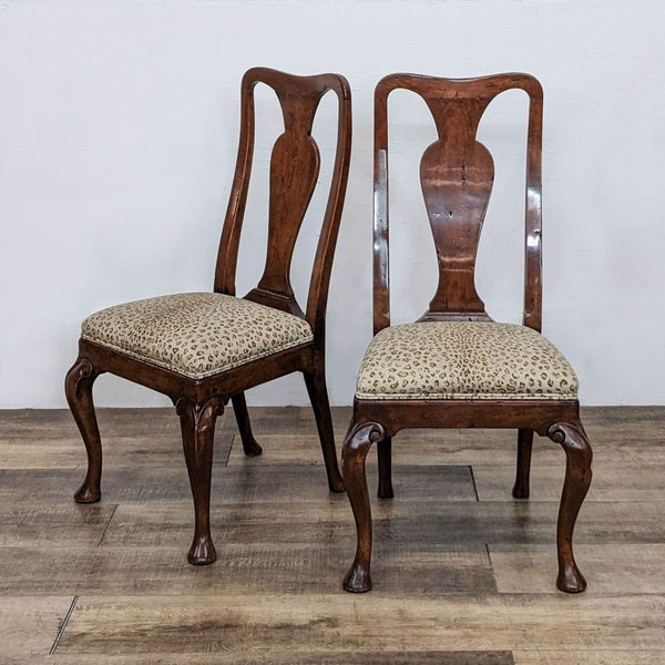 Two Queen Anne style dining chairs by Reperch with leopard print seats and wooden frames, on a wooden floor.