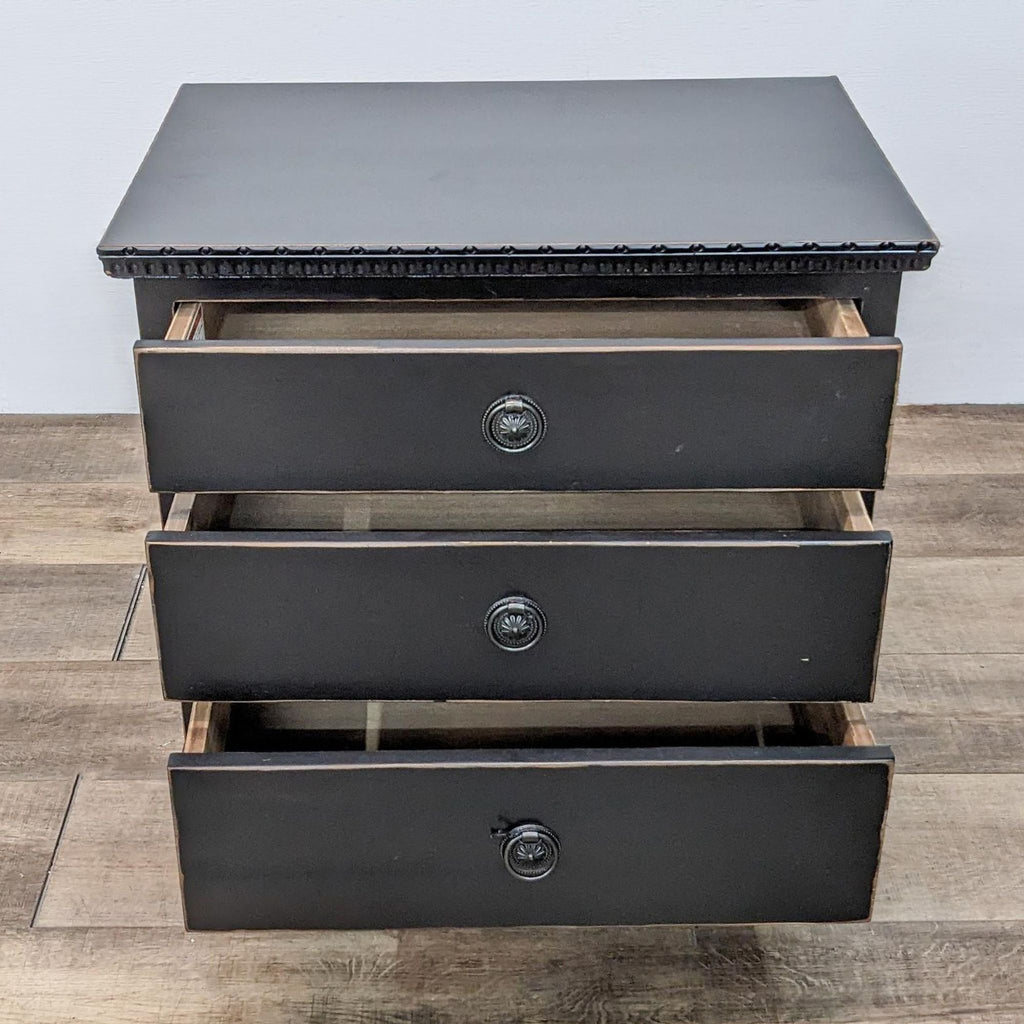 Three-drawer Harvest end table with open drawers showing storage space and decorative top edge, on a wooden floor.