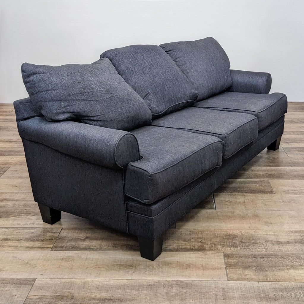 Angle view of a compact 79" grey sofa by Living Spaces, highlighting its roll arm design and dark finish feet.