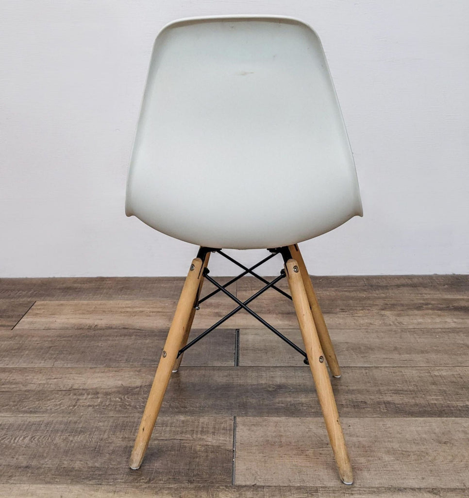 Reperch white dining chair with moulded seat and wooden Eiffel-style legs from a back angle.