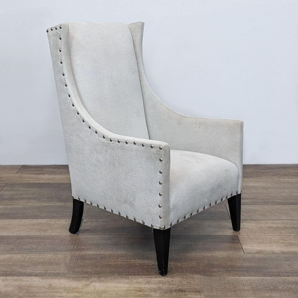Alt text 2: Side view of the Reperch wingback chair showing the curve of the backrest, linen upholstery, and decorative nailhead details, on a wooden floor with a grey wall.
