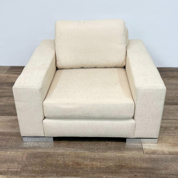 Frontal view of a Yountville chair by Reperch with block arms, deep seat, angled back, upholstered in beige fabric on chrome feet.