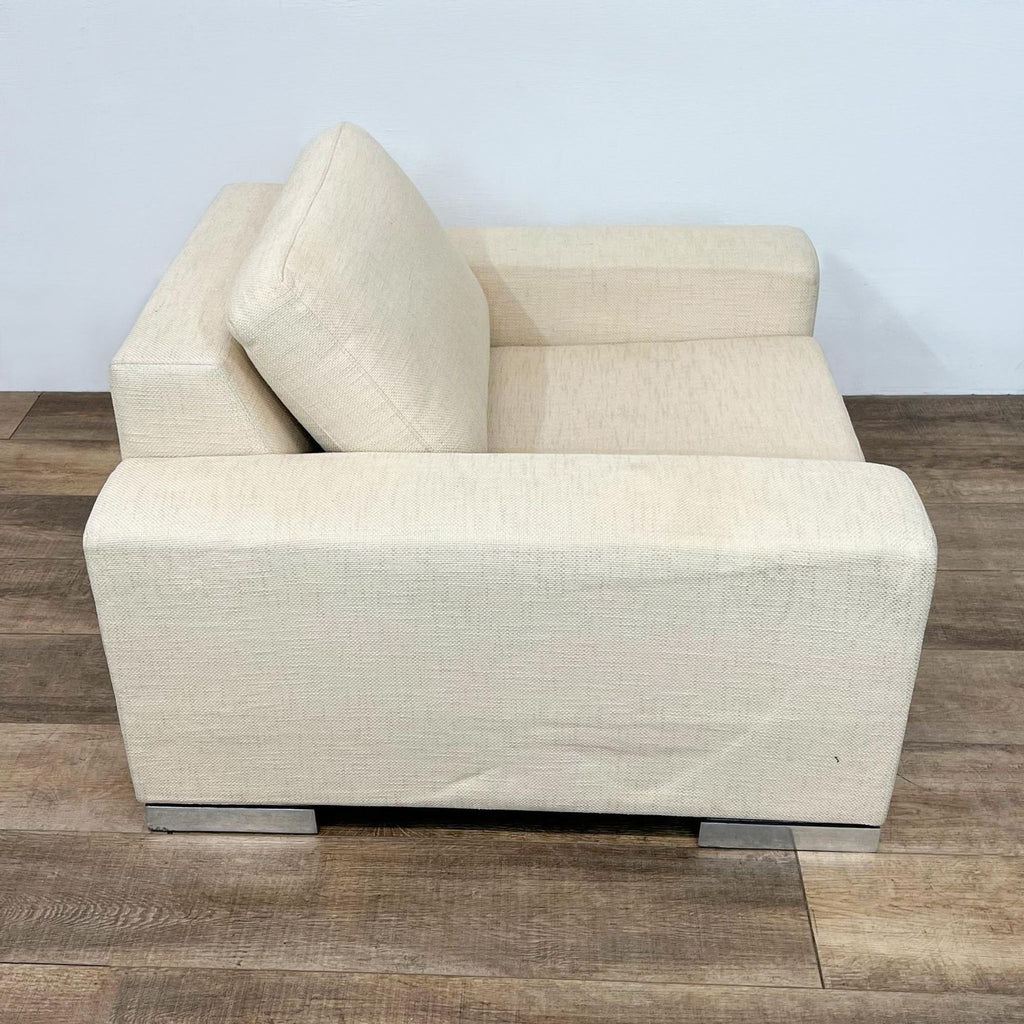 Angled side view of a beige Yountville lounge chair by Reperch showing the block arms, deep cushioning, and chrome block feet.
