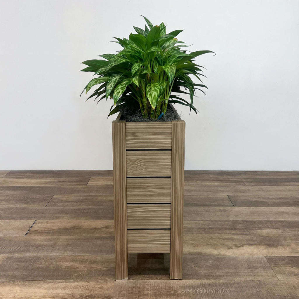 OFS Intermix planter with solid wood slat construction filled with lush greenery on a wooden floor.