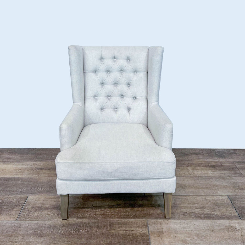 Modern Arhaus wingback chair with button tufting and nailhead details on textured fabric, wooden legs visible.