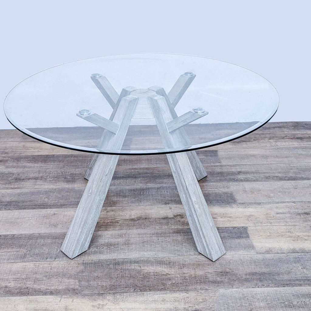 Reperch Beaumont dining table with a round tempered glass top and sun-drenched bleached solid acacia wood flaired legs.