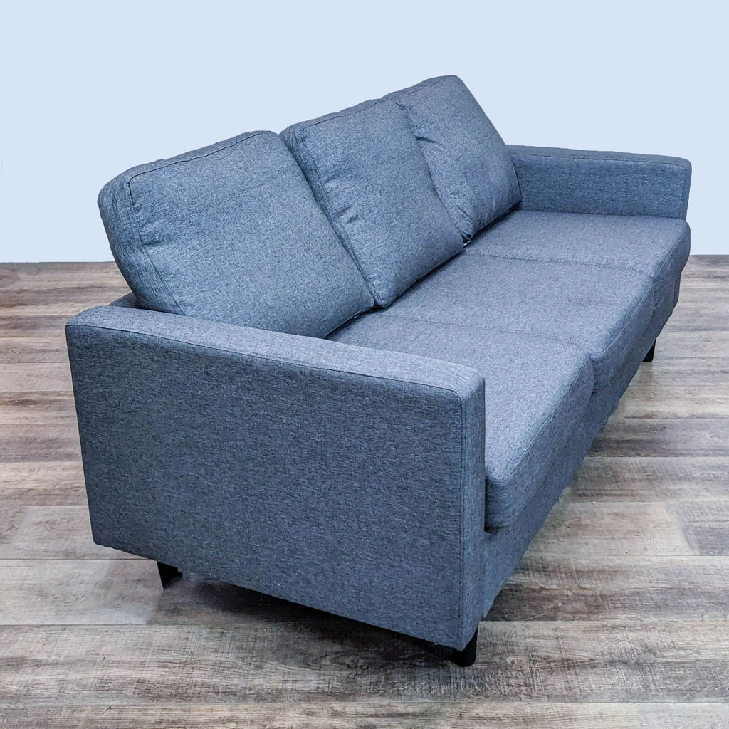 Three-seat narrow arm Reperch sofa with a side view, highlighting its dark legs on a wooden floor.