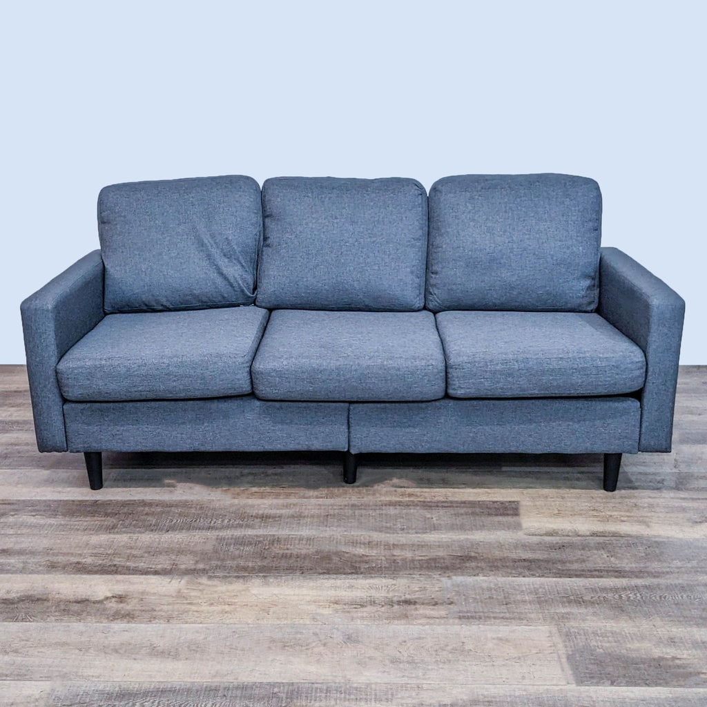 Three-seat Reperch sofa with narrow arms and dark finish feet, shown from the front against a wood floor.