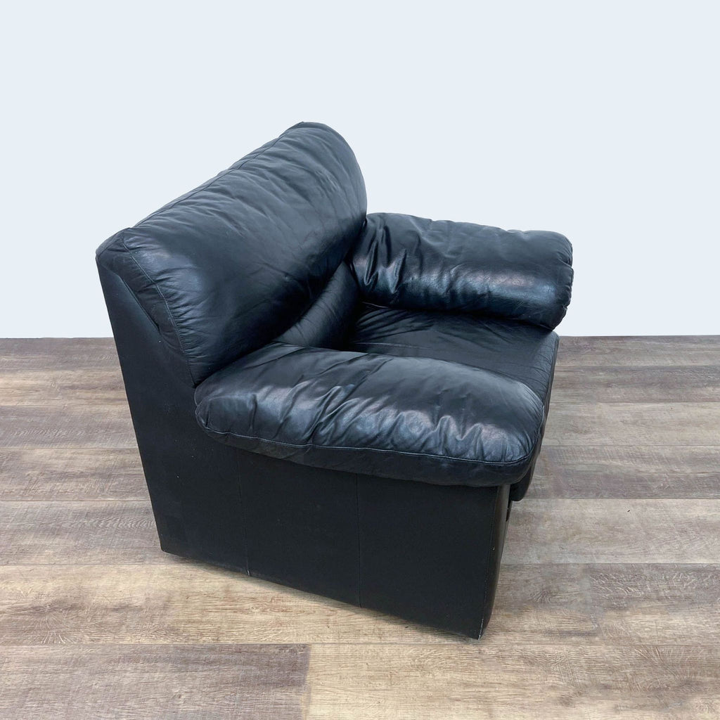Black leather Reperch armchair with side view on wooden floor.