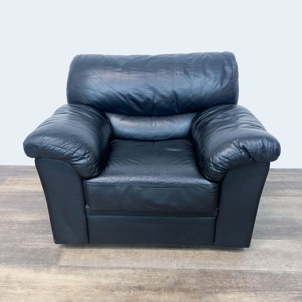 Alt text: Black leather armchair from Reperch brand placed on a wooden floor against a white background, part of lounge furniture.