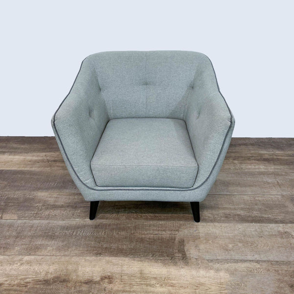 Ace Interior mid-century club chair with cushioned seat and button tufted back in gray on wood floor.