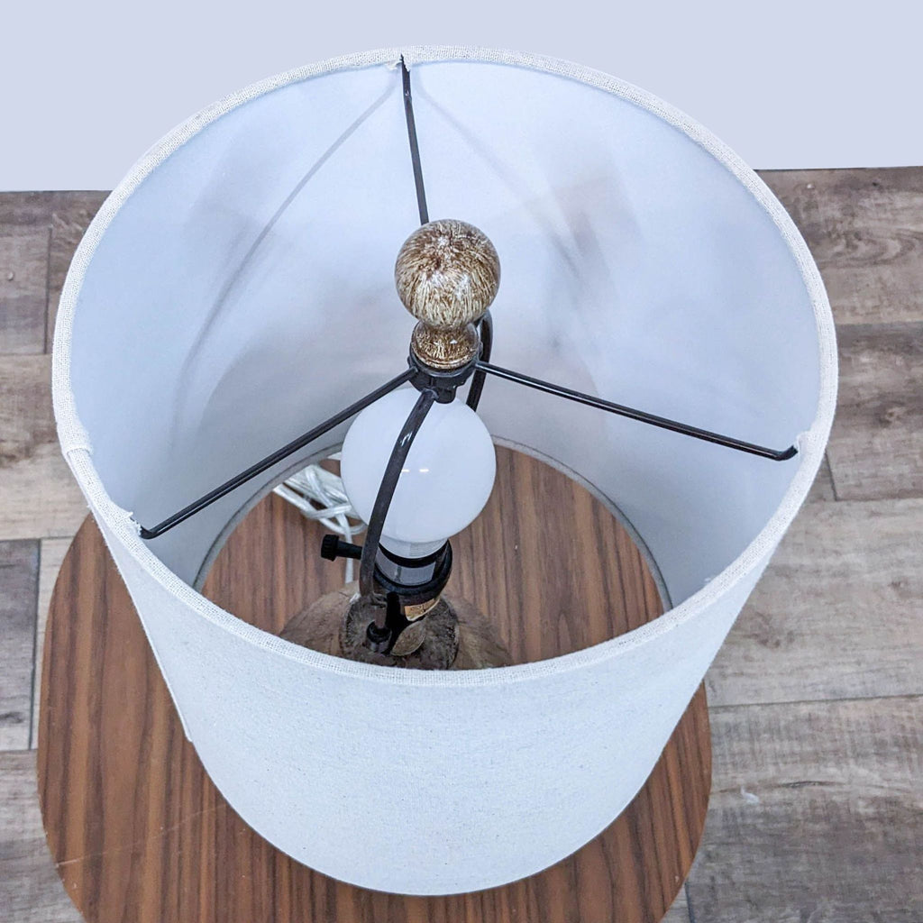 Top view of a Reperch lamp showing a white lampshade interior with a round bulb and lamp fixtures on a wooden surface.