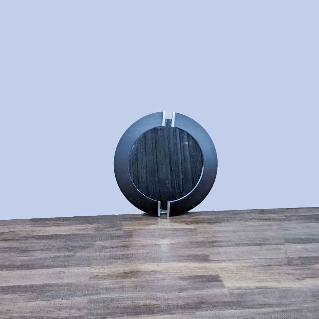 Reperch brand round mirror with dark frame and metal accents, placed on a wood floor against a grey wall.