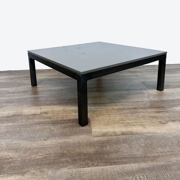 Room & Board coffee table with a sleek stone top and black steel legs positioned on wooden flooring.