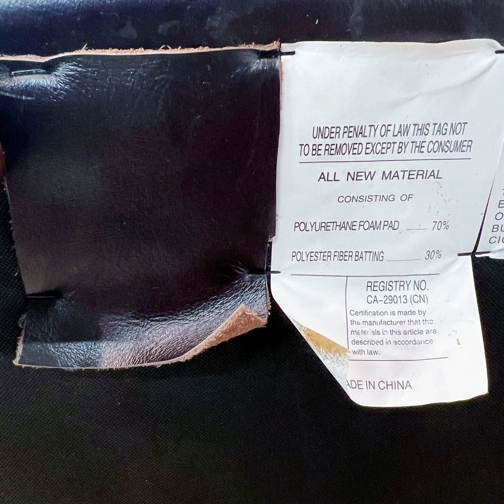 Close-up of a Reperch brown leather ottoman's tag showing materials and legal notice.