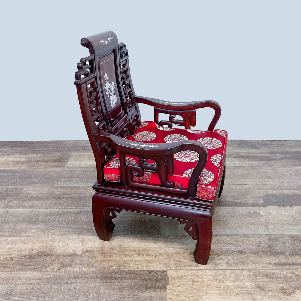 Side view of a Reperch Oriental rosewood armchair with elaborate carvings, mother of pearl details, and a red cushion.