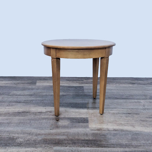 Contemporary Ethan Allen maple end table with round top on a grey wood floor.