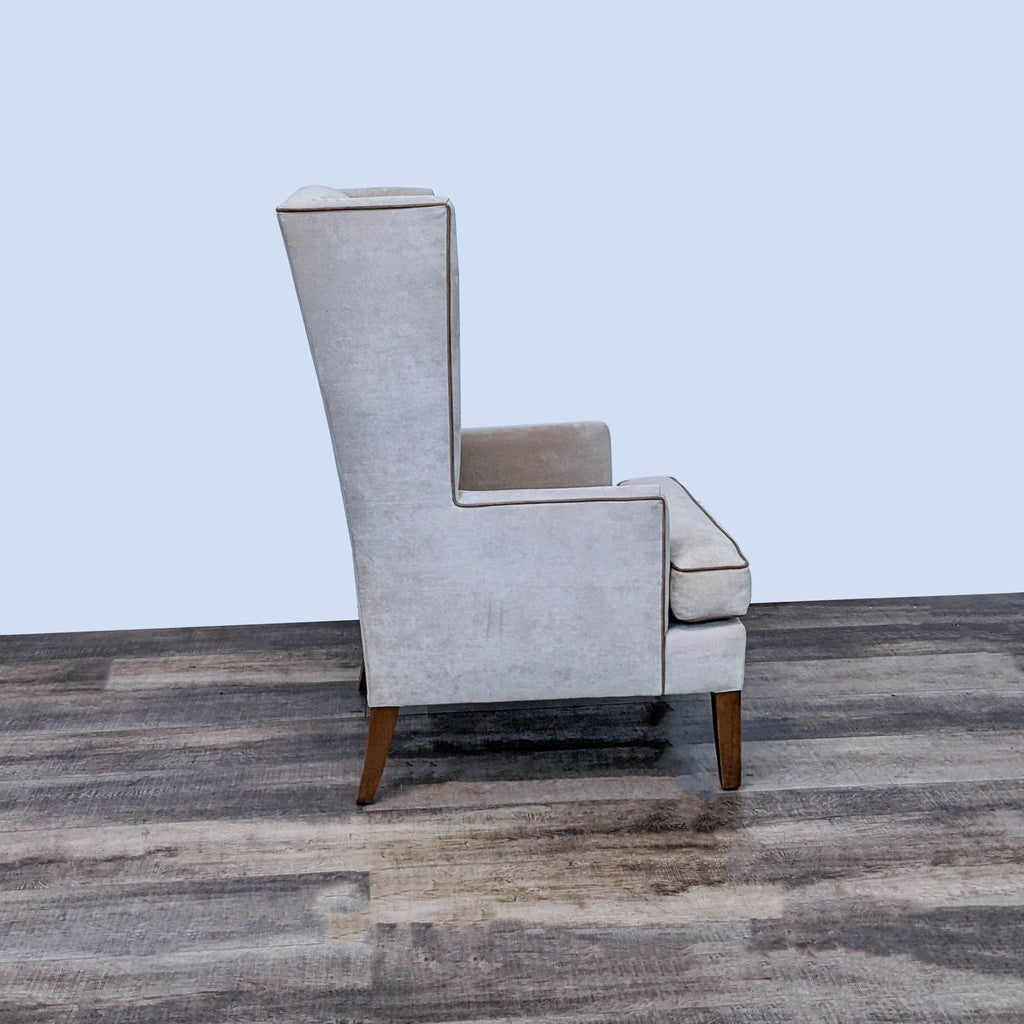 Side view of Reperch modern wingback chair with clean lines, plush seating, and wooden legs on a wooden floor.