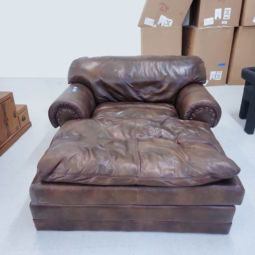 Reperch brown leather oversized chaise lounge with plush cushioning and nailhead trim rolled arms, displayed in a room with boxes.