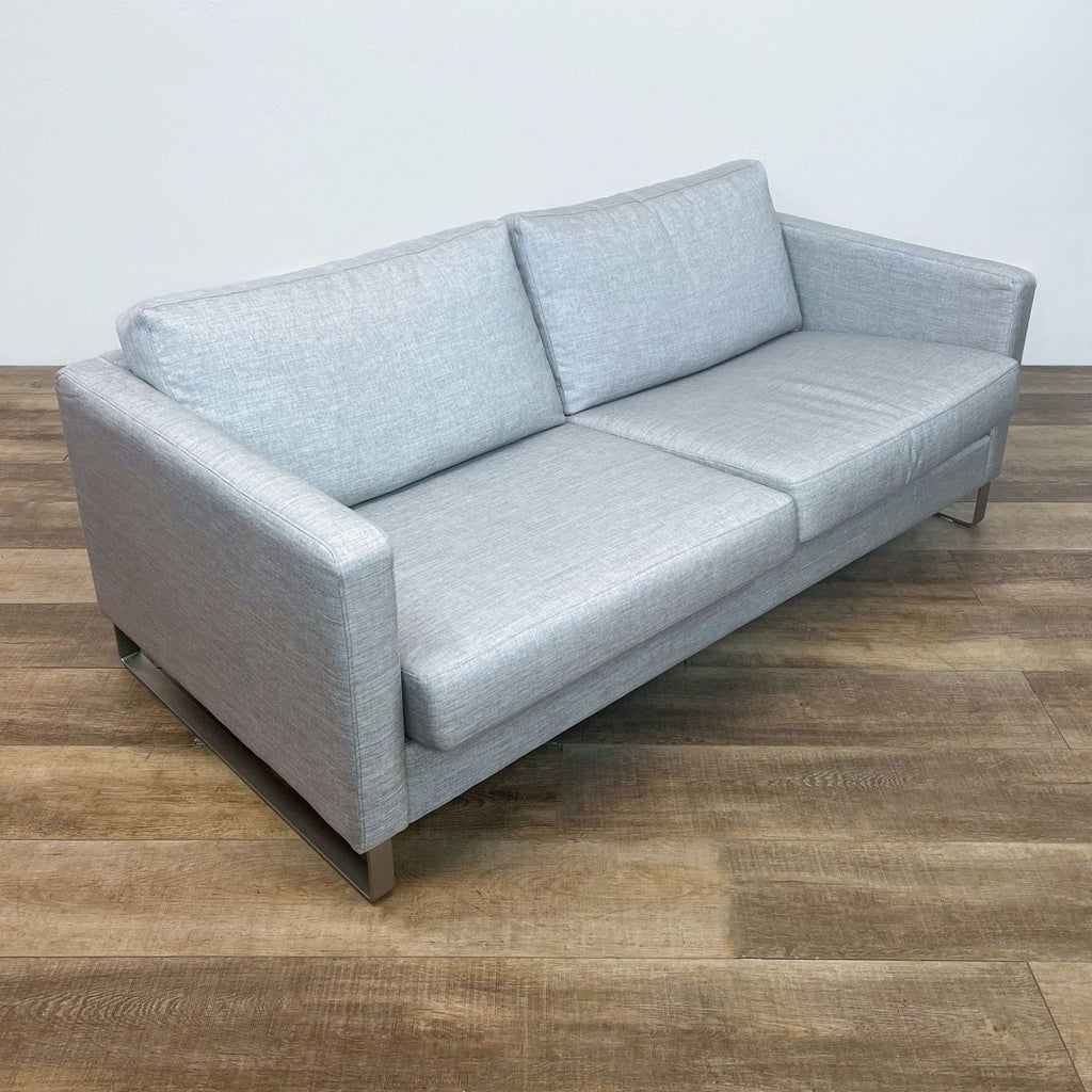 Alt text 2: Angled view of a BoConcept Danish-designed gray 3-seat sofa with sleek metal legs on a wooden floor.