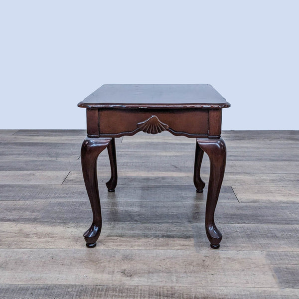 Reperch end table with cabriole legs and scalloped apron on a wooden floor.