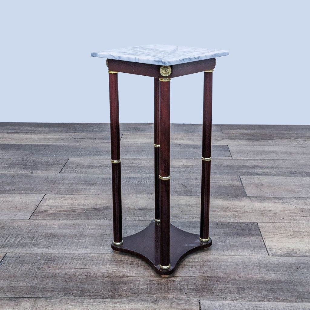 Reperch brand end table with a marble top and brass embellishments on its wooden legs, set against a wood floor.