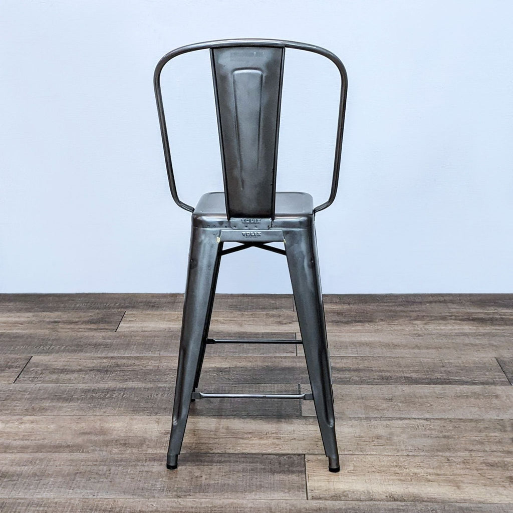 Tolix high-back stool with steel frame, designed by Xavier Pauchard, on a wooden floor.