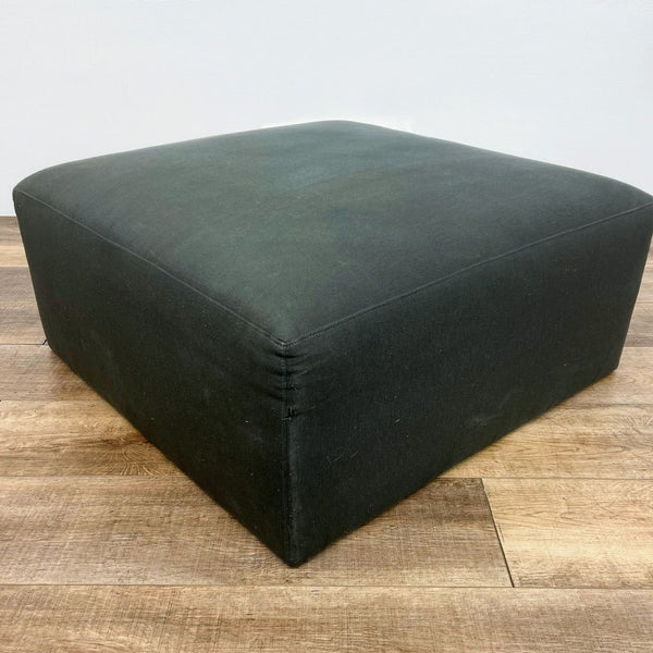 Crate & Barrel modern gray square ottoman on wood flooring, 35 inches, suitable as a coffee table.
