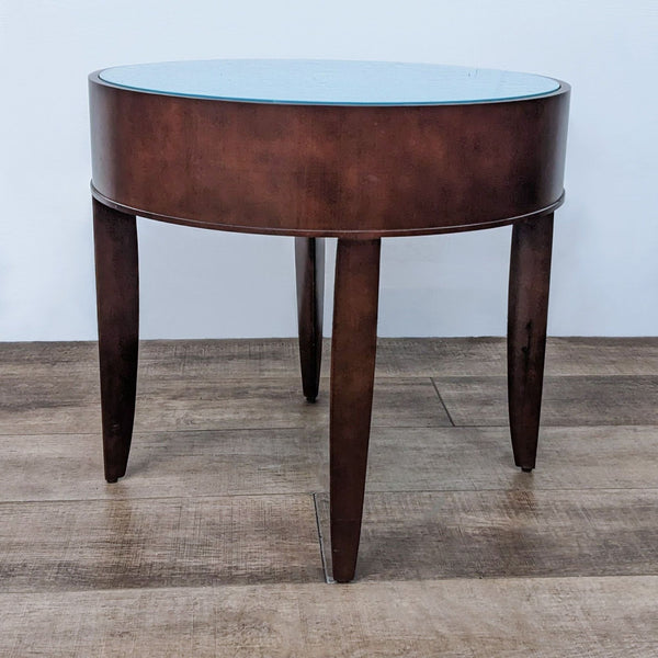 Round Reperch end table with glass top and dark wooden legs on wooden floor.