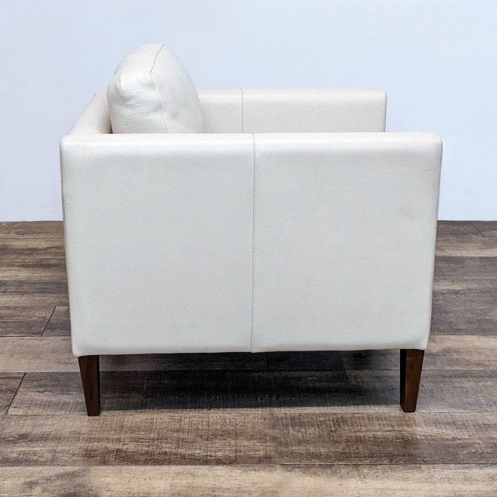 Rear view of a Room & Board Kent lounge chair in white leather with a modern design and walnut finish legs.