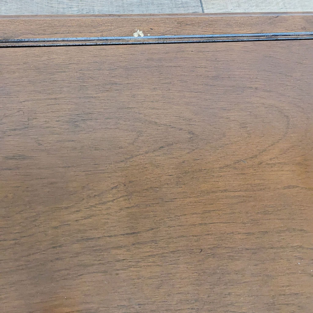 Close-up of Reperch coffee table's faux drawer with carved apron and metal knob on wood surface.