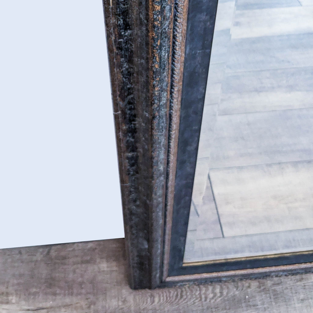 Classic elegance Art & Frame Co. mirror, dark wooden framed, leaning against wall in interior setting.