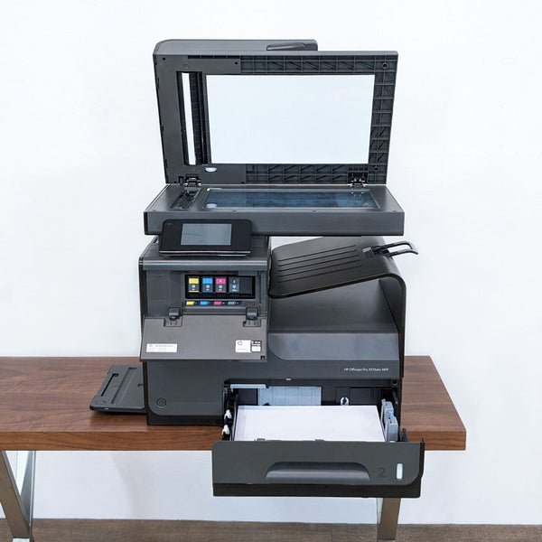 Gently used HP OfficeJet Pro X576dw MFP with open scanner lid on a table, showcasing touchscreen and paper tray.