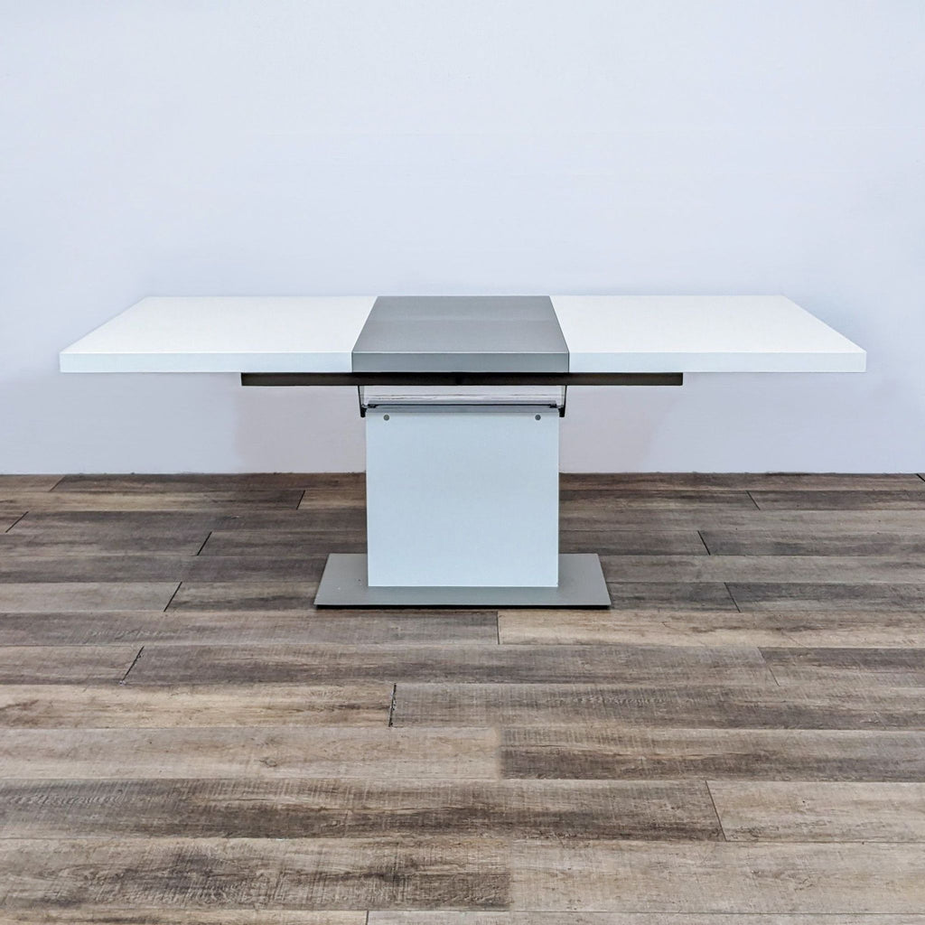 BoConcept Milano extendable dining table partially opened, showing the mechanism and white tabletop on a wooden floor.