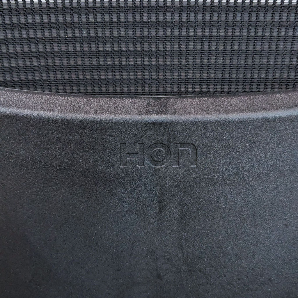 Close-up of HON logo on a modern barstool with stretch mesh back and durable steel frame.