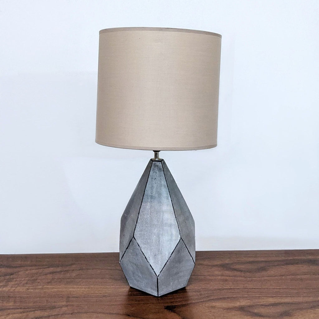 Reperch brand table lamp with a beige shade and geometric metal base on a wooden surface.