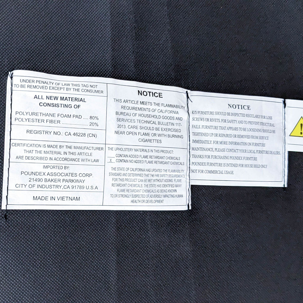 Label tags on a Laurel Foundry dark grey fabric ottoman detailing material and safety notices.