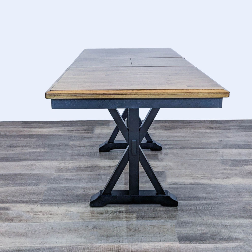 Winners Only dining table with natural wood finish and black base, expandable with a drop-in leaf.