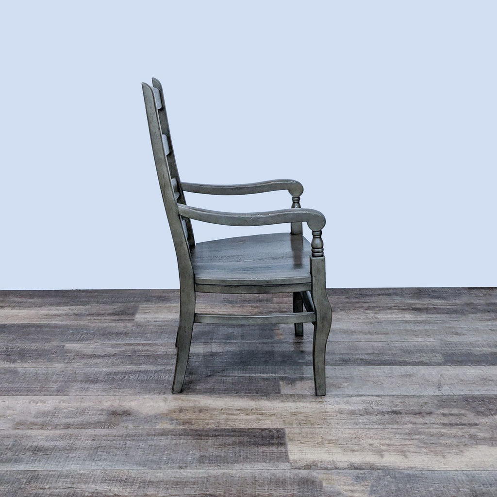 Solid wood Pottery Barn dining chair with a ladderback, spindle detail, and armrests in early-American style, positioned on wood flooring.