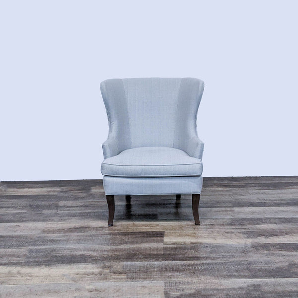 1. Contemporary Ballard Designs wingback lounge chair with neutral upholstery and dark wooden legs on a wooden floor.