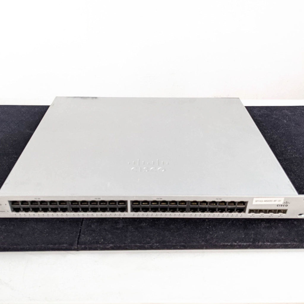 Front-facing Cisco network switch featuring a line of connectivity ports, placed on a black surface.