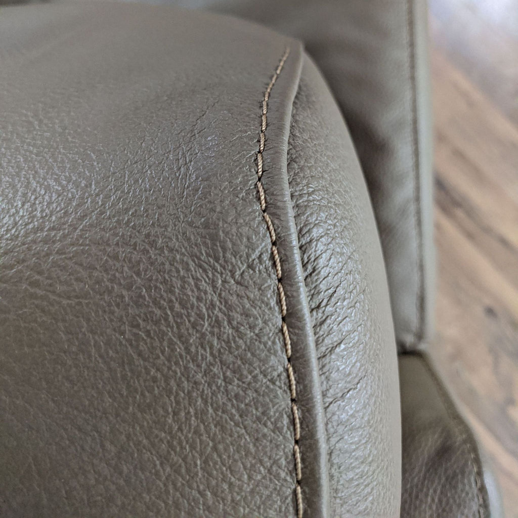 3. Close-up on the detailed stitching of a taupe leather DIMA Salotti chair's armrest.