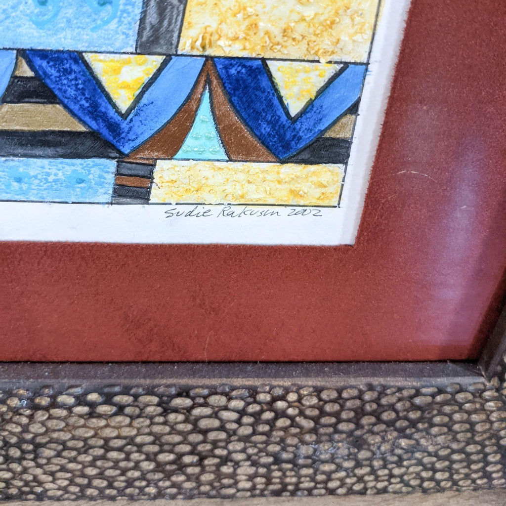2. Close-up of the artwork’s bottom corner showing the artist's signature "Sudie Rakusin 2002" on the mat.