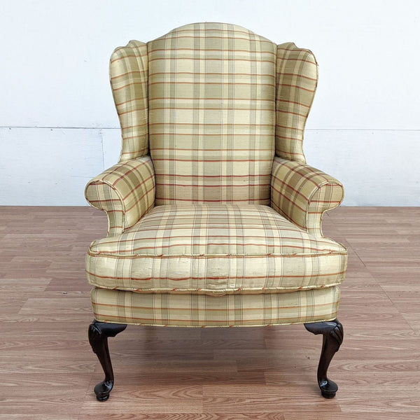 Alt text 1: Drexel brand lounge chair with plaid upholstery and frayed fabric on the armrest, set against a white wall and wooden floor.