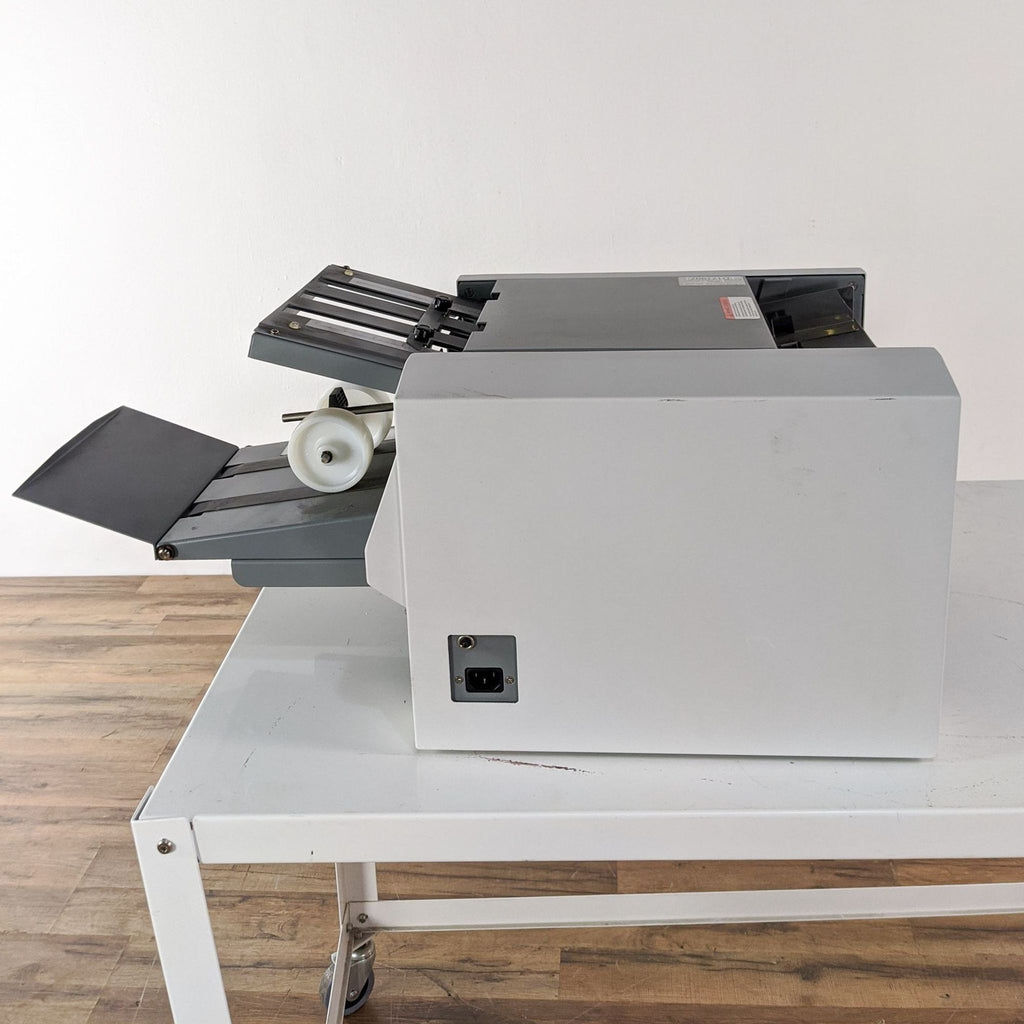 2. Side view of a Formax printer on a white table showing power input and paper exit tray.