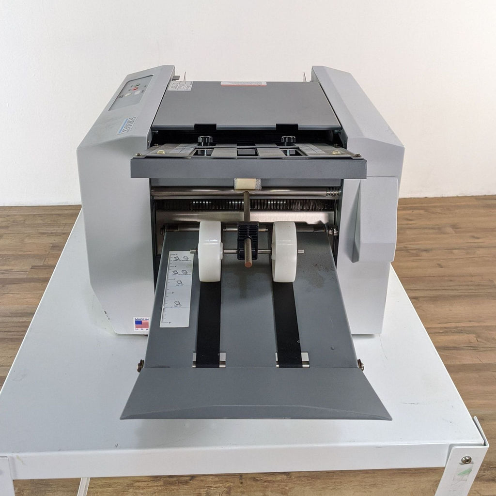 1. Formax printer on a white table, viewed from front, with open feed tray and control icons visible.