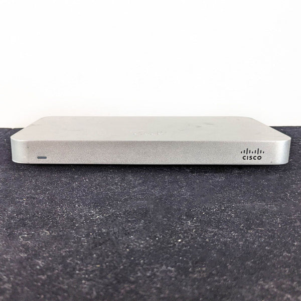 1. Cisco networking device on a black surface with a visible logo and LED indicator on the front.